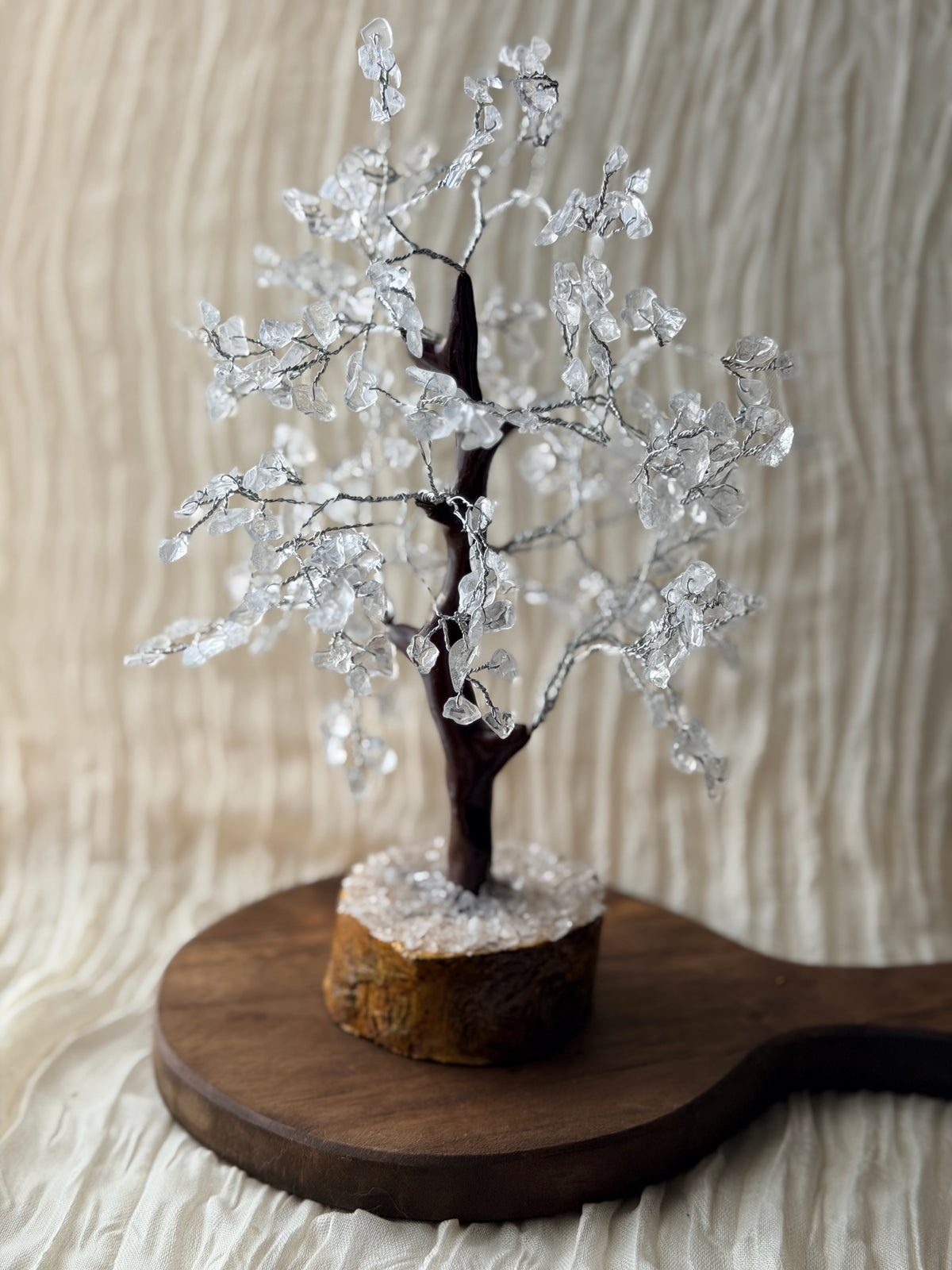 Handgemaakte bergkristalboom met heldere steentjes op een houten voet